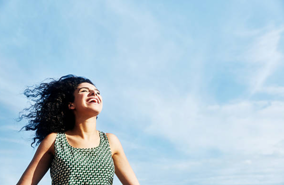 a woman standing in a field with her hair blowing in the wind