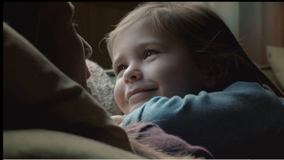 a little girl sitting on a couch next to a woman