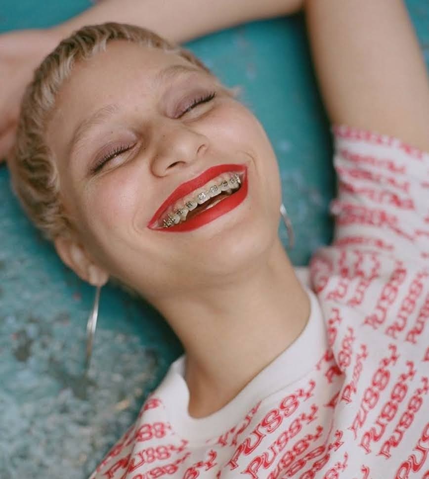 a woman laying on a bed with a toothbrush in her mouth