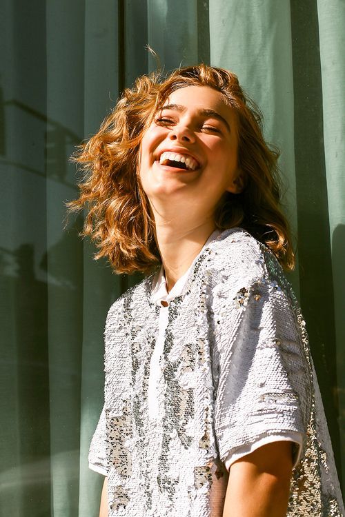 a woman laughing while standing in front of a curtain