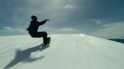 a man riding a snowboard down a snow covered slope