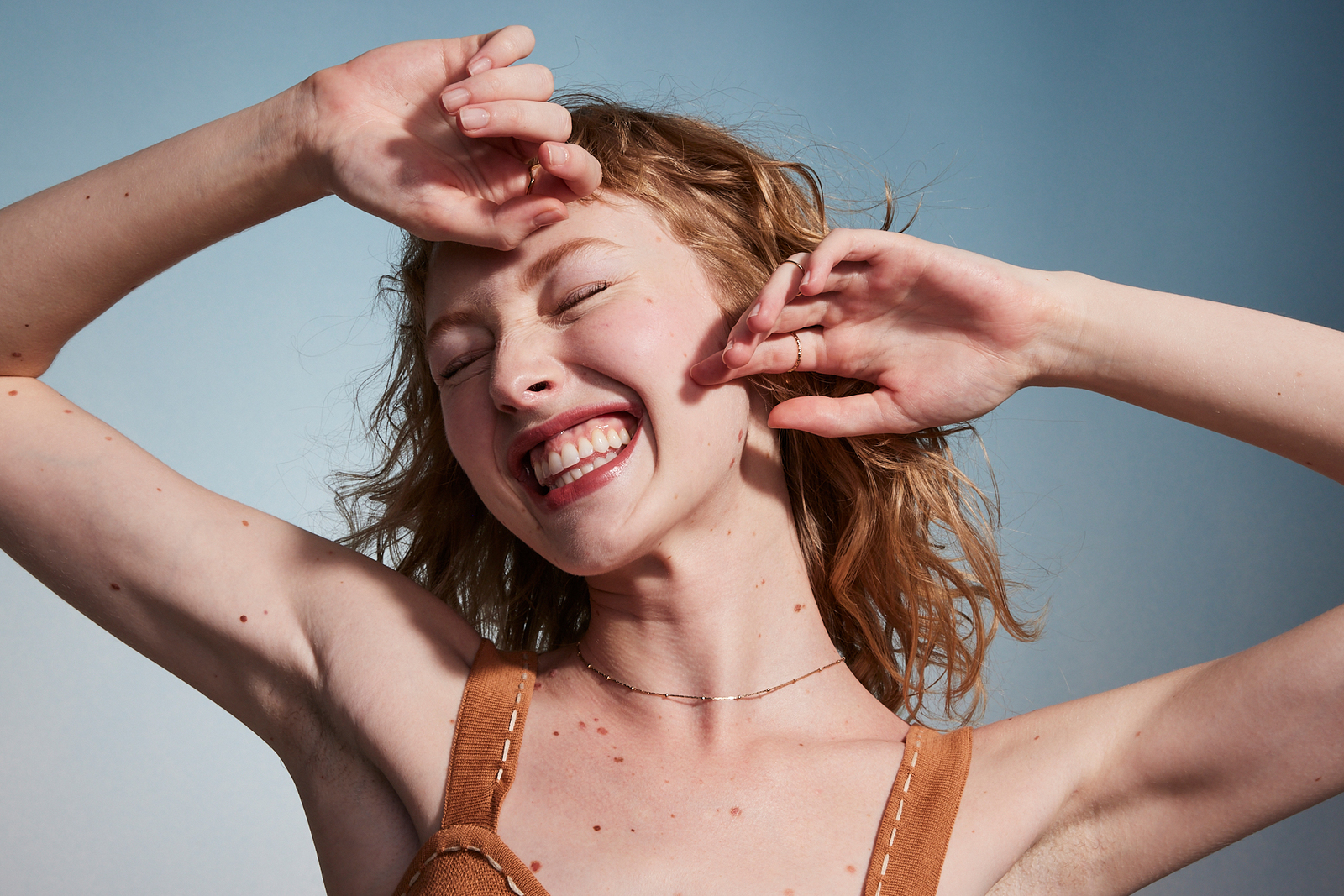 a woman with her hands on her head smiling