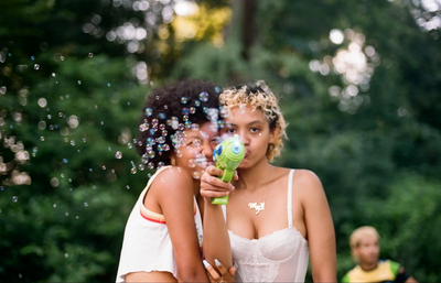 two women blowing bubbles in a park