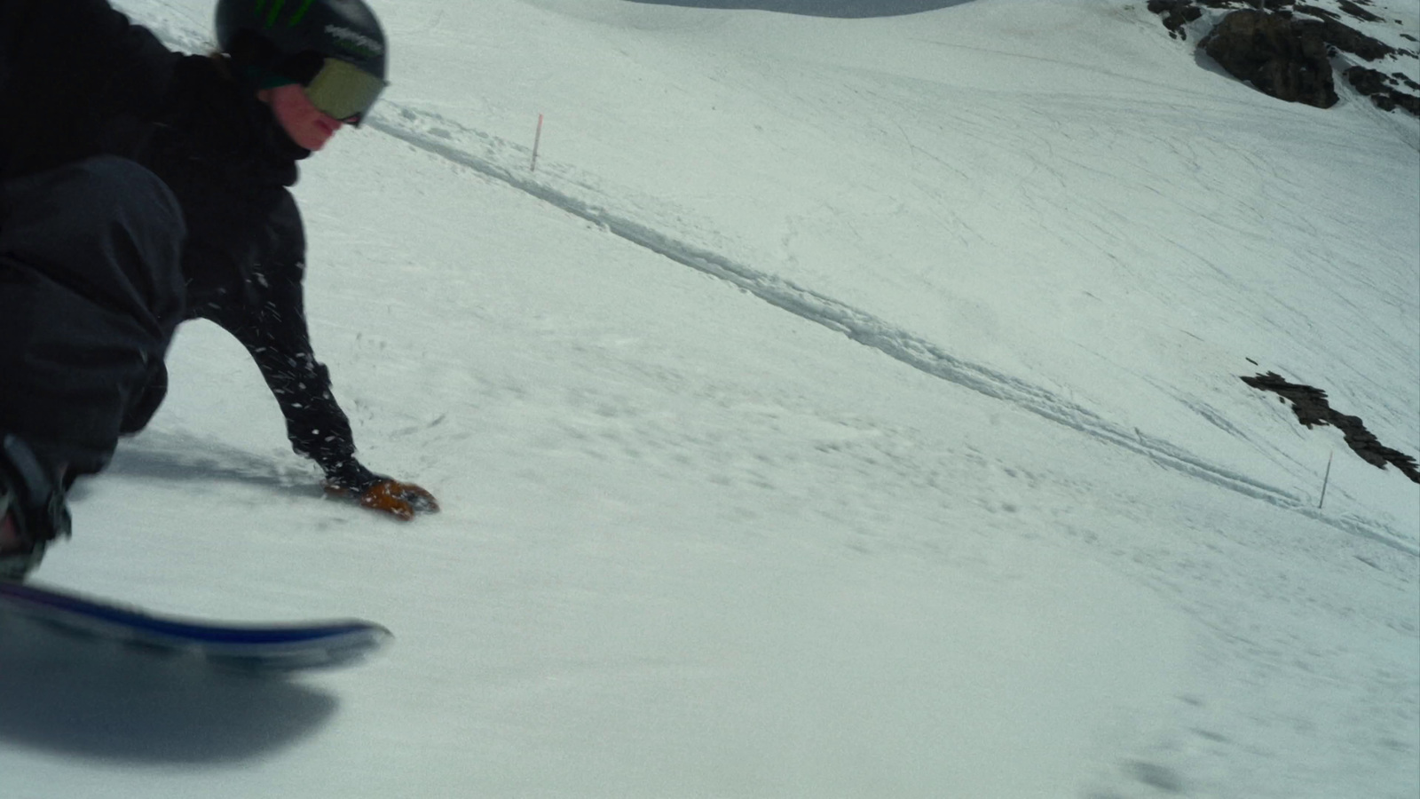 a man riding a snowboard down a snow covered slope