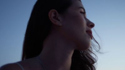 a woman with long hair standing in front of a blue sky