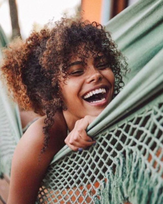 a woman smiling while laying in a hammock