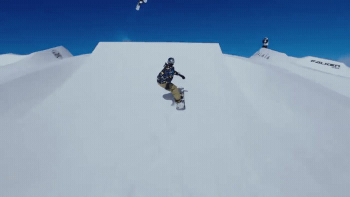 a man riding a snowboard down the side of a snow covered slope