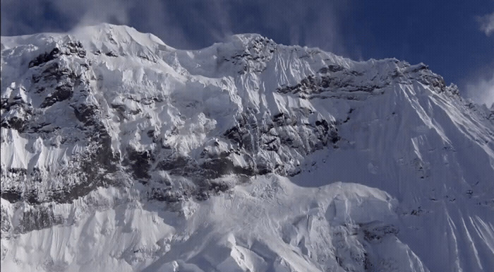 a large mountain covered in snow under a blue sky