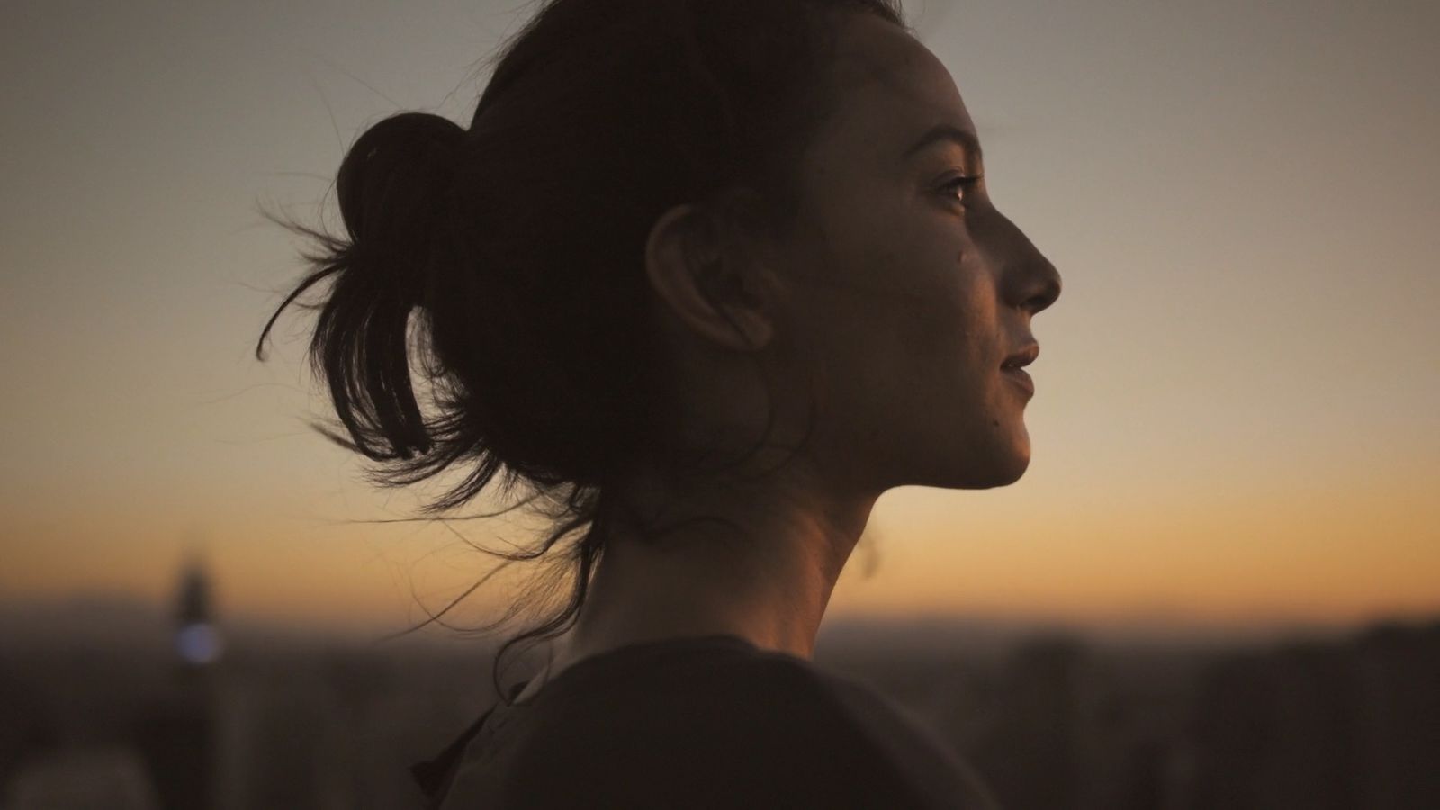 a woman standing in front of a sunset