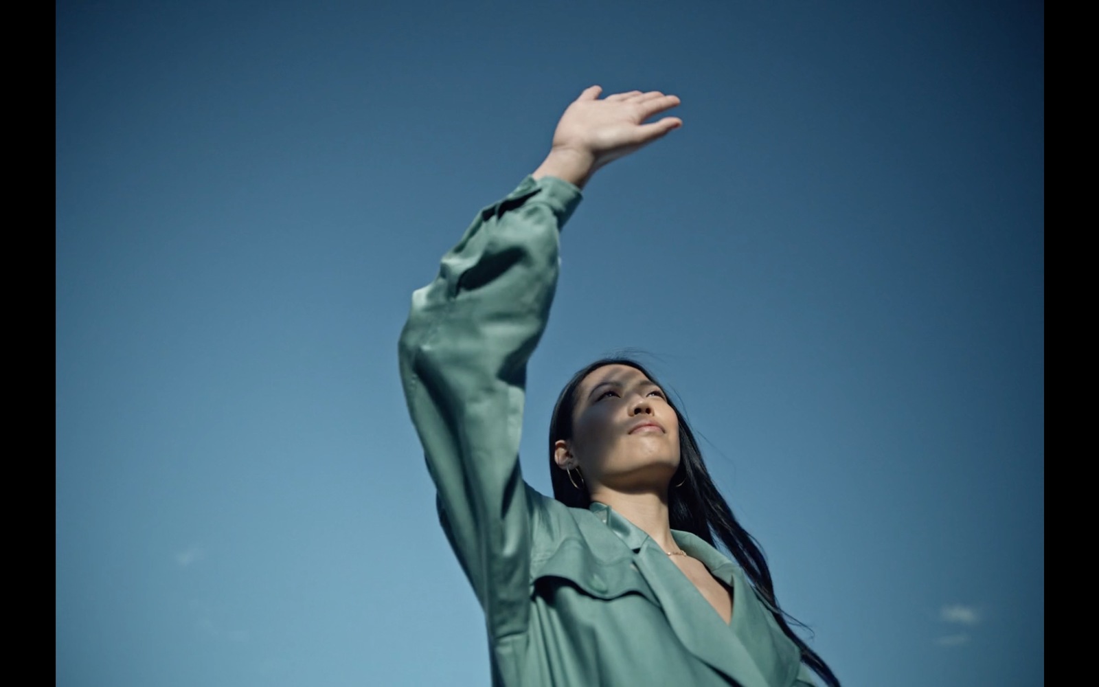 a woman reaching up to catch a frisbee