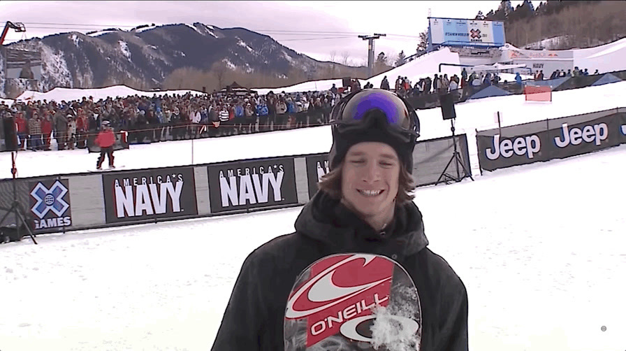 a man holding a snowboard in front of a crowd of people