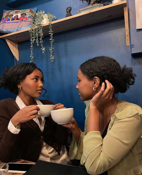 two women sitting at a table drinking coffee