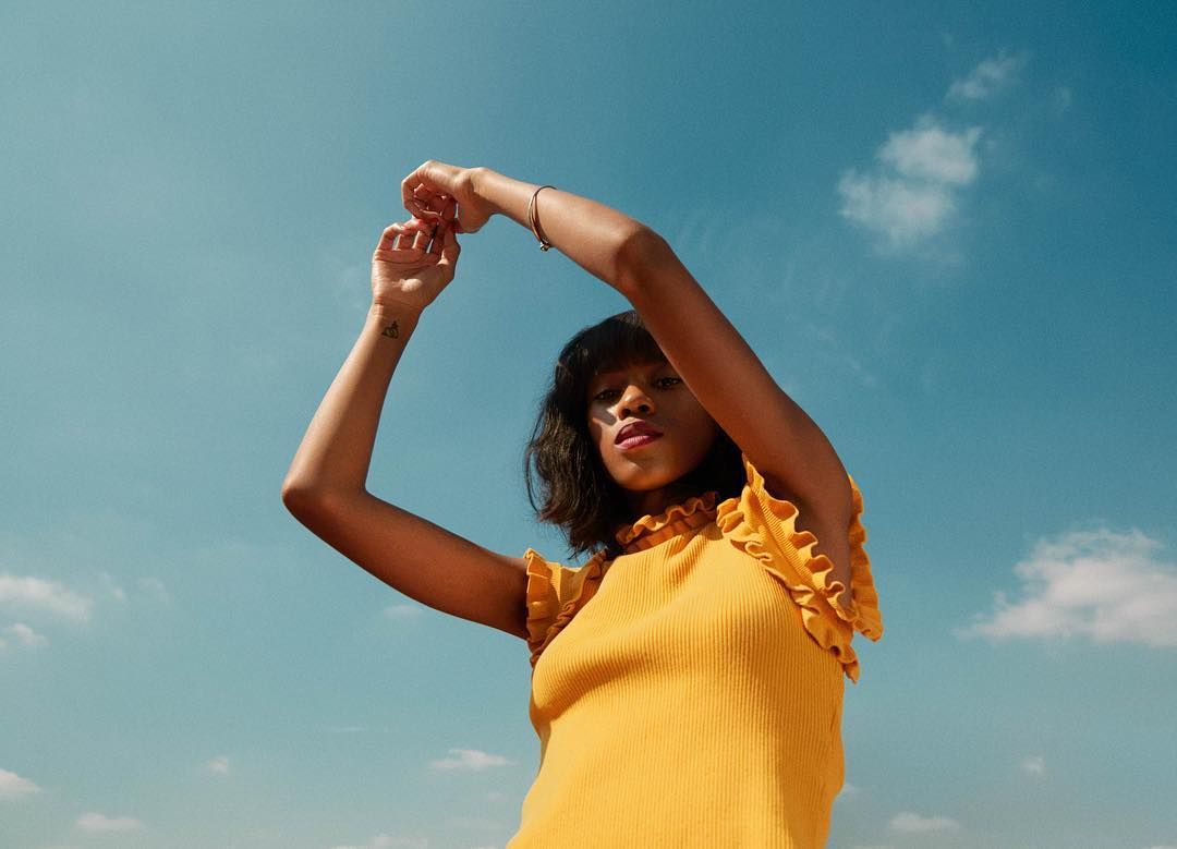 a woman in a yellow shirt is posing for a picture