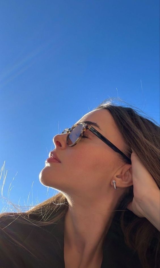 a woman wearing sunglasses looking up into the sky