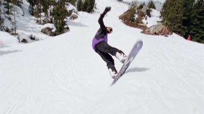 a snowboarder in a purple jacket is doing a trick