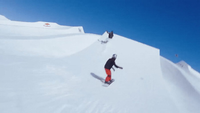 a man riding a snowboard down the side of a snow covered slope