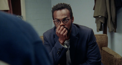 a man in a suit and glasses sitting in front of a mirror