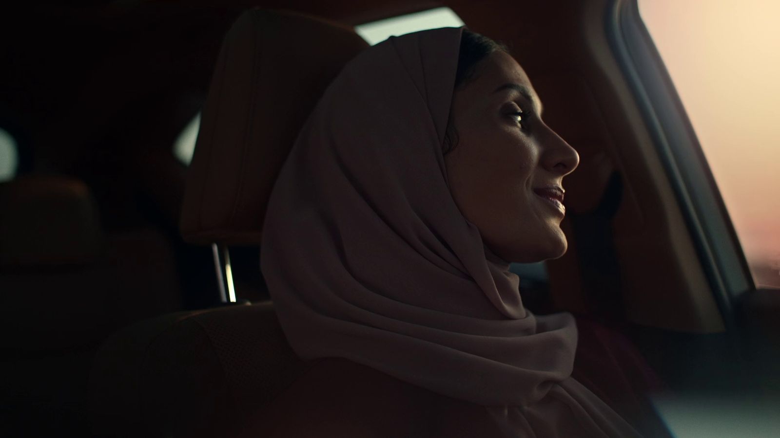 a woman sitting in a car wearing a headscarf