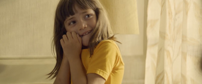 a little girl sitting on a couch with her hands on her face