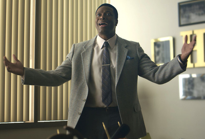 a man in a suit and tie standing in front of a window