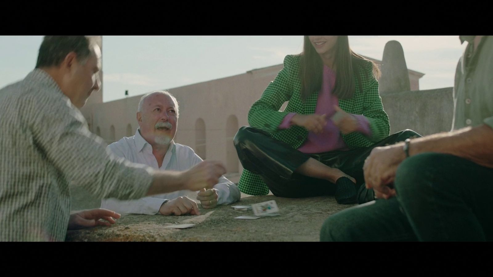 a group of people sitting on the ground playing cards