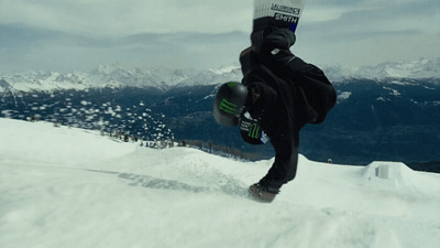 a man riding a snowboard down the side of a snow covered slope