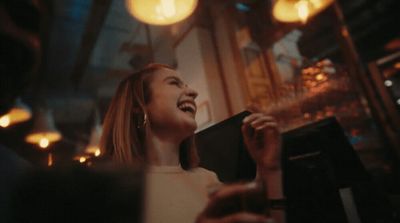 a woman laughing while holding a book in her hand