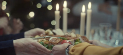 two people holding a plate of food with candles in the background