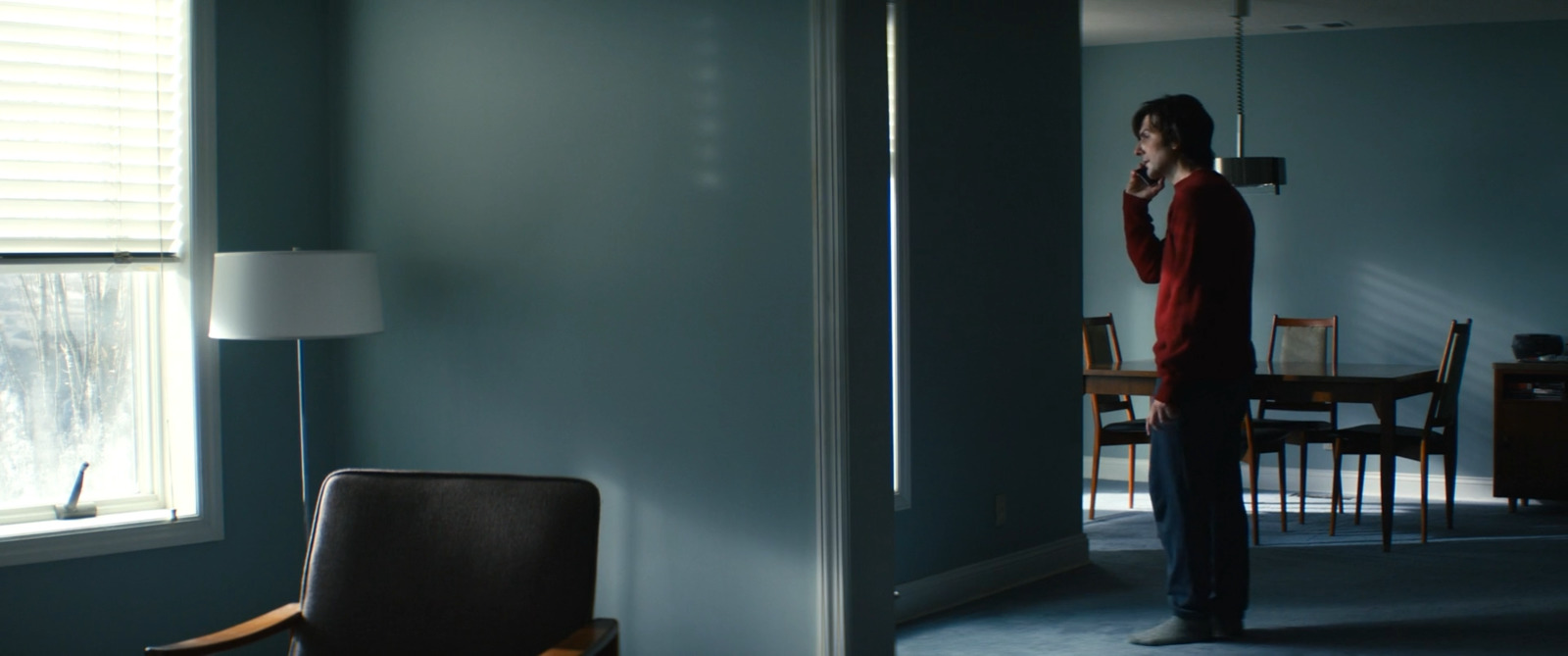 a man standing in a living room talking on a cell phone