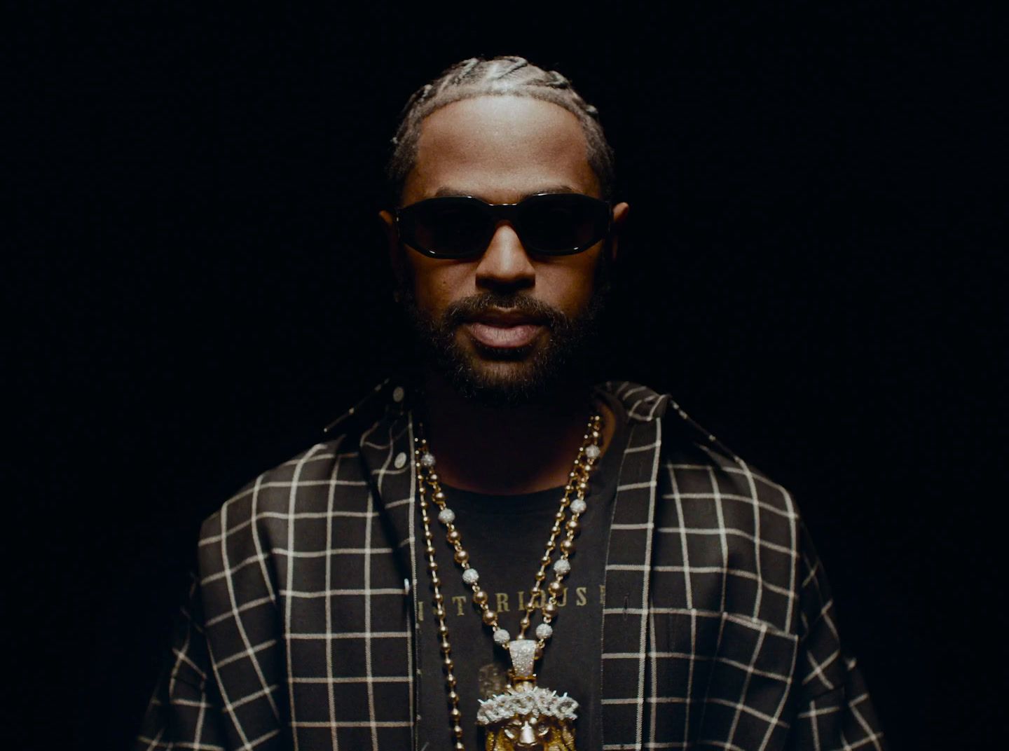 a man with a beard wearing a necklace and sunglasses