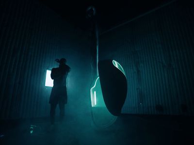 a man standing in a dark room next to a vase