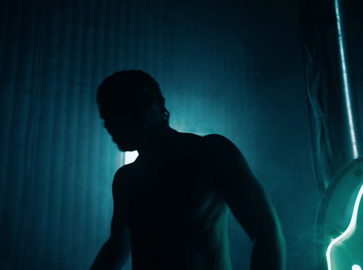 a man standing in a dark room next to a guitar