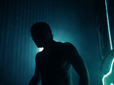 a man standing in a dark room next to a guitar