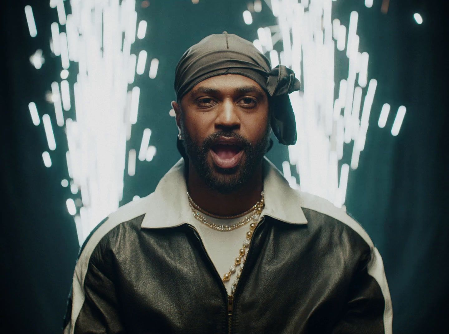 a man in a black leather jacket and bandana making a funny face