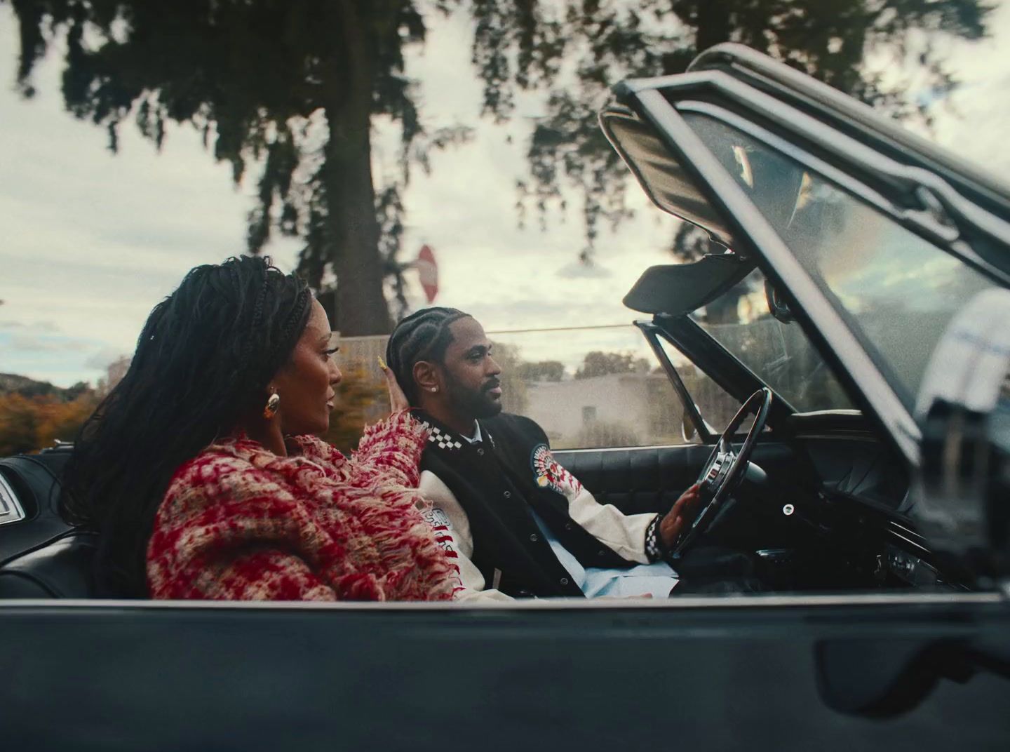 a man and a woman sitting in a convertible car