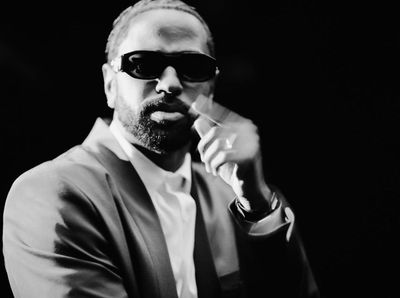 a man in a suit and sunglasses smoking a cigarette