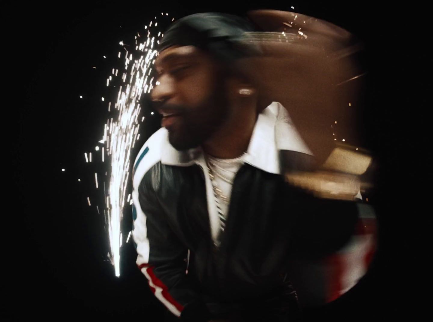 a man in a leather jacket and hat with fireworks in the background