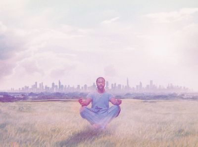 a man sitting in a field in front of a city