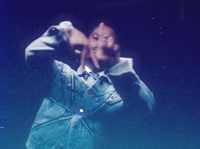 a man in a jean jacket making a face with his hands