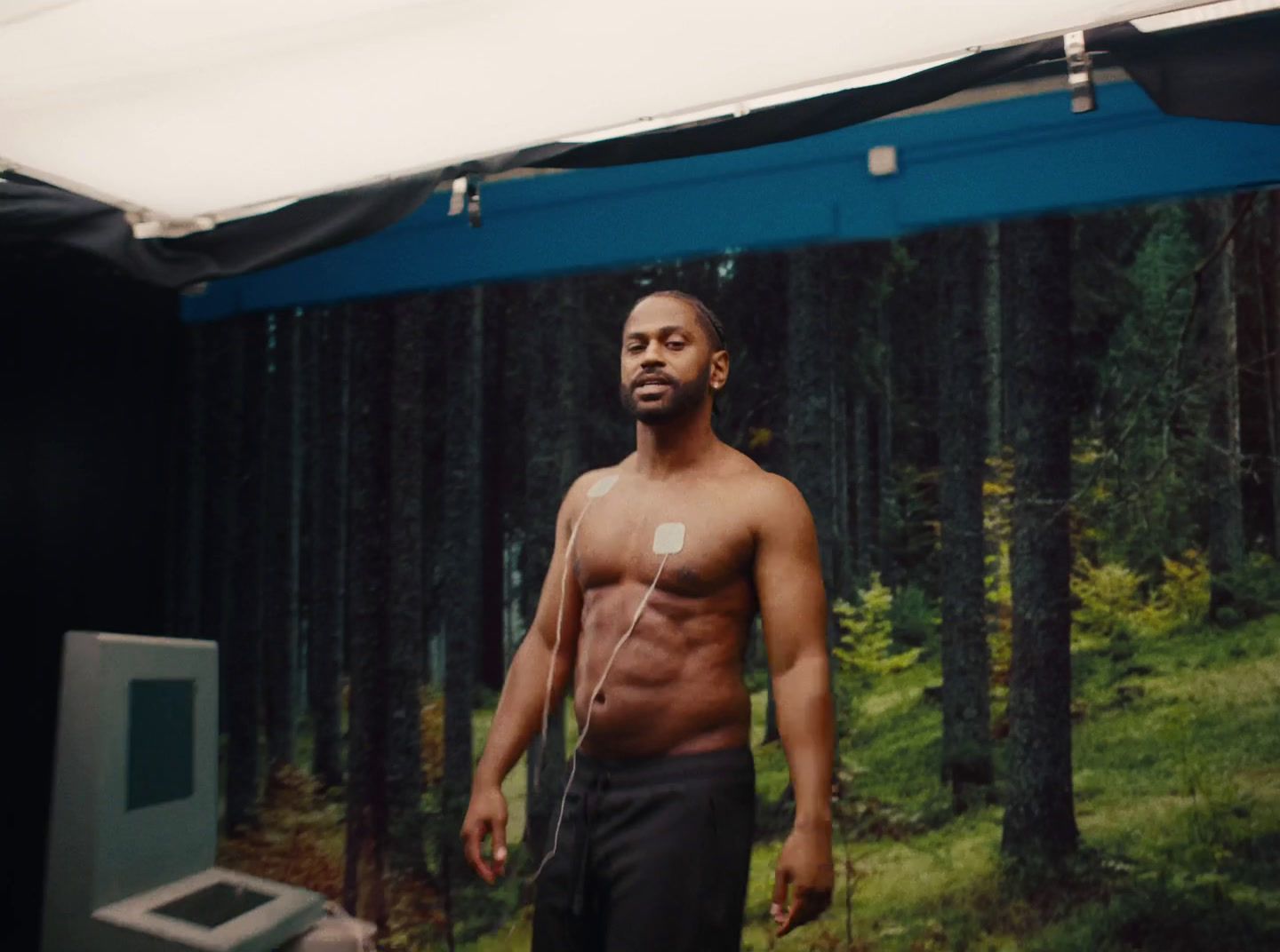 a man without a shirt standing in front of a screen