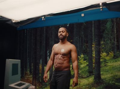 a man without a shirt standing in front of a screen