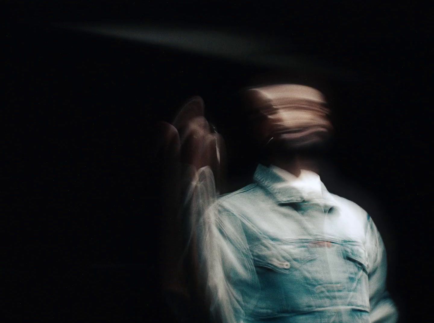 a blurry image of a man in a denim shirt