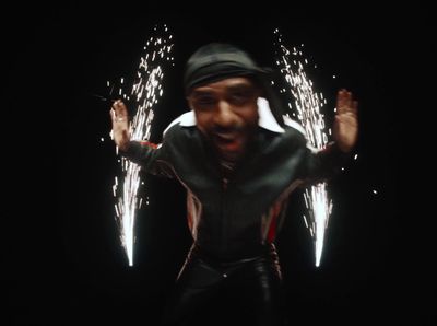 a man with his hands in the air with fireworks in the background