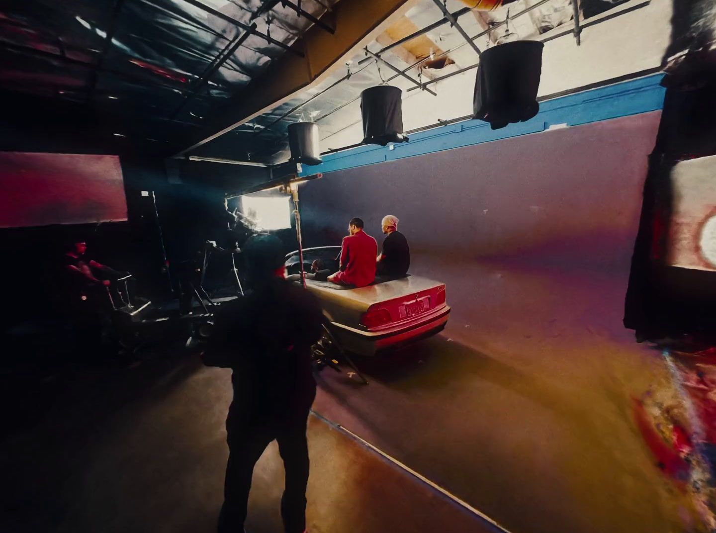 two men standing next to a car in a garage