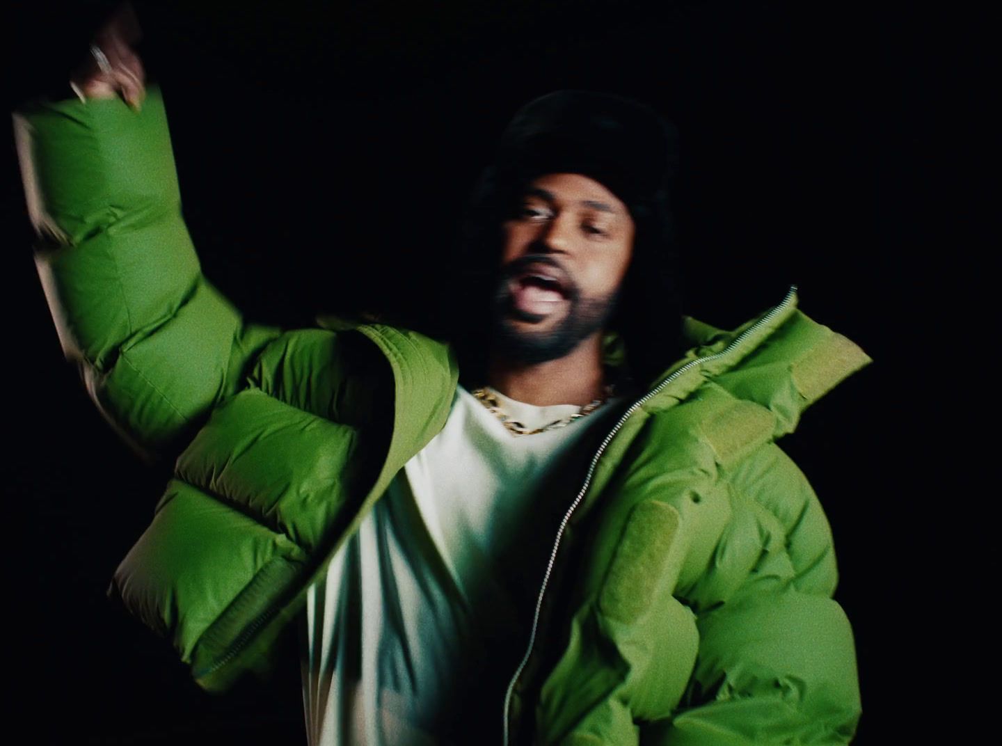 a man wearing a green jacket and a white t - shirt