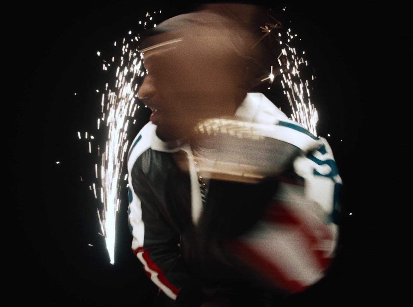 a man in a leather jacket with fireworks in the background