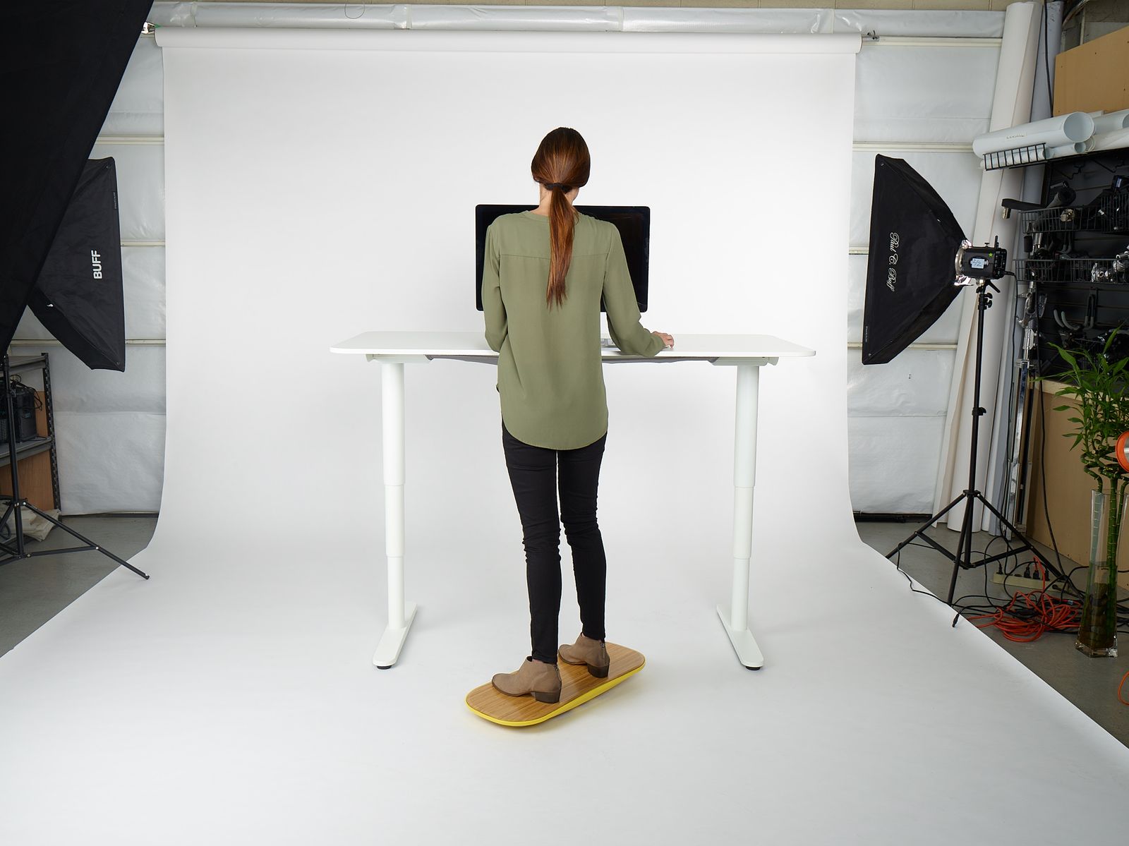a woman standing at a desk in front of a camera