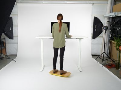 a woman standing at a desk in front of a camera