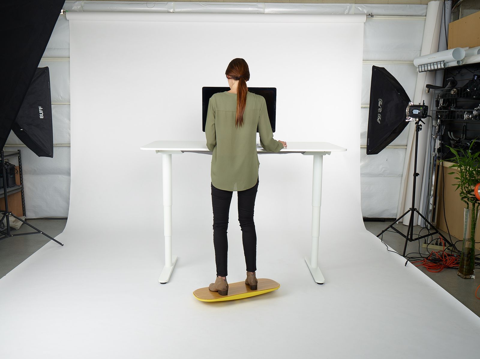 a woman standing at a desk in front of a camera