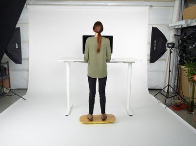 a woman standing at a desk in front of a camera